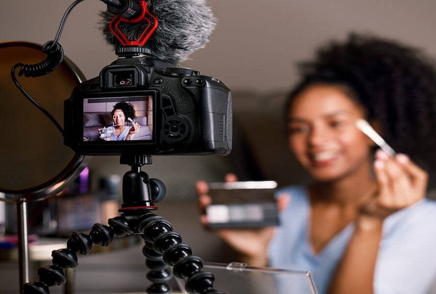 Fashion blogger reviewing makeup products, sitting in front of a dslr camera and mirror
